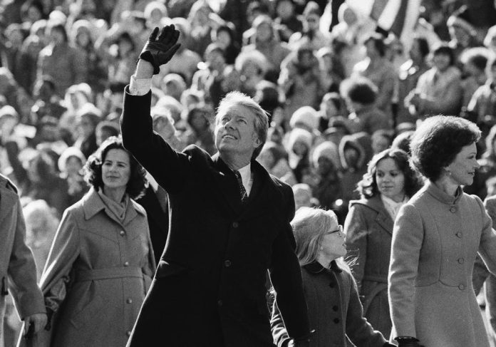 ARCHIVO - El presidente estadounidense Jimmy Carter saluda a la multitud mientras camina con su esposa Rosalynn, y su hija, Amy, a lo largo de la Avenida Pennsylvania tras su investidura, el 20 de enero de 1977, en Washington. (AP Foto/Suzanne Vlamis, archivo)
