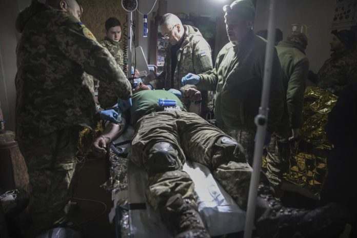 Los médicos asisten a un soldado ucraniano herido cerca de Bájmut, el lugar donde se libran fuertes batallas entre las tropas rusas y ucranianas, en la provincia de Donetsk, Ucrania, el 27 de febrero de 2023. (AP Foto/Yevhen Titov)